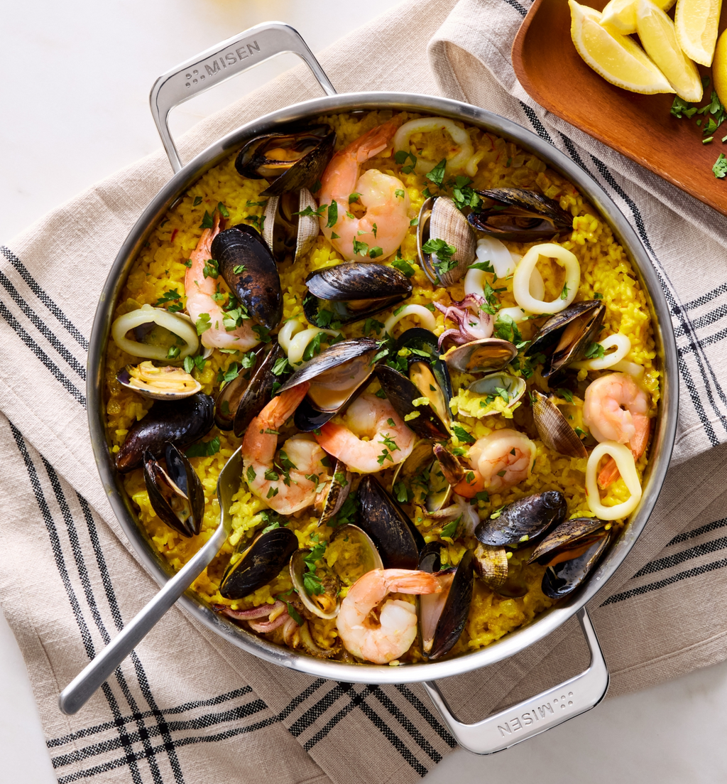 Seafood paella with shrimp, mussels, clams, and calamari in a Misen stainless steel pan